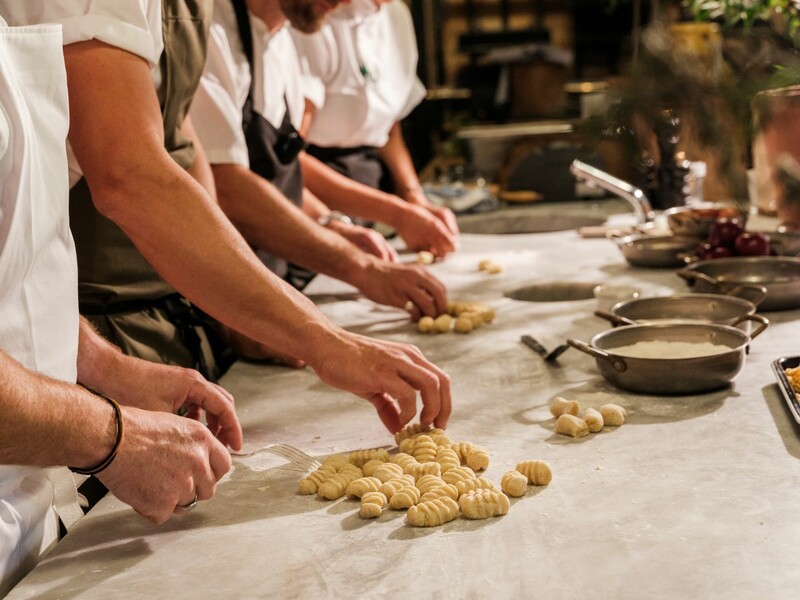 Chefs at Da Costa restaurant in Bruton, Somerset, preparing handmade gnocchi on a marble countertop, with hands shaping and pressing the dough with forks.